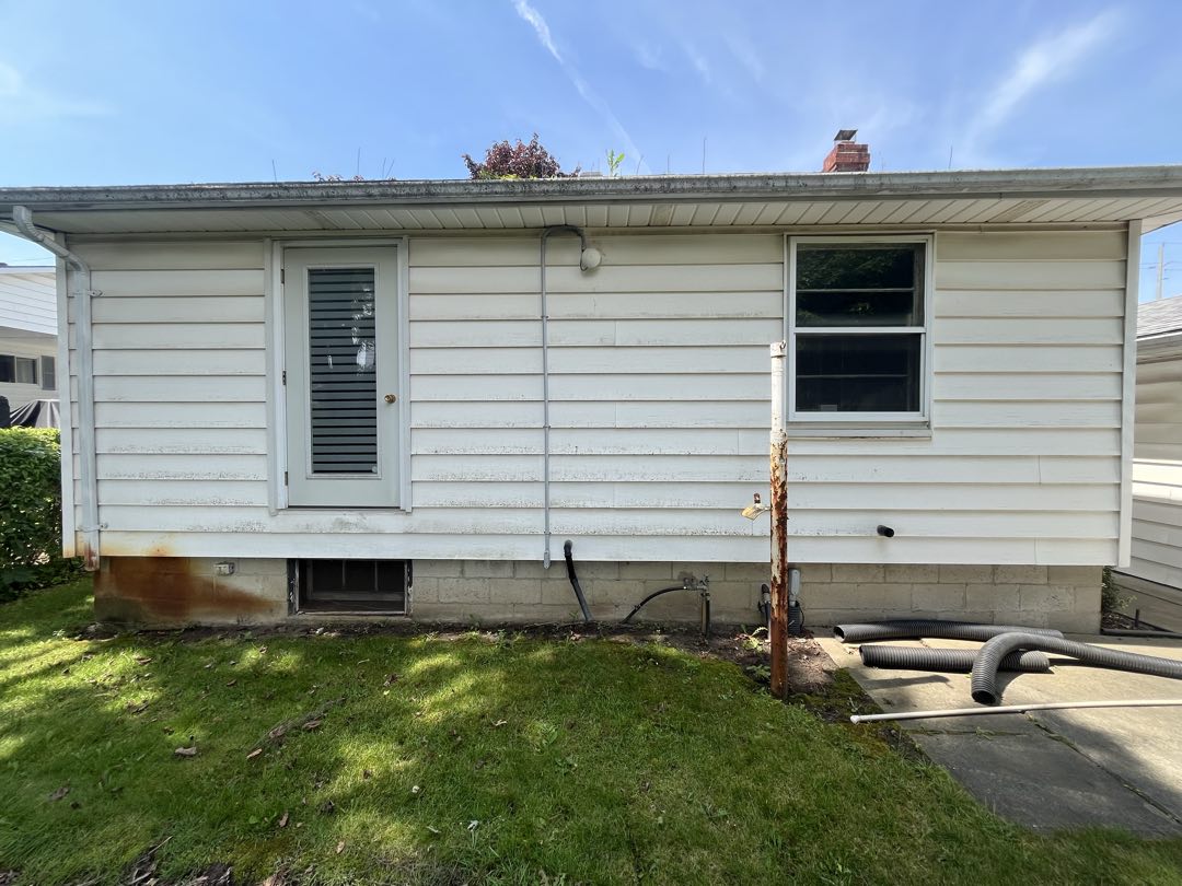 Rear of a house with staining and dirty siding before cleaning