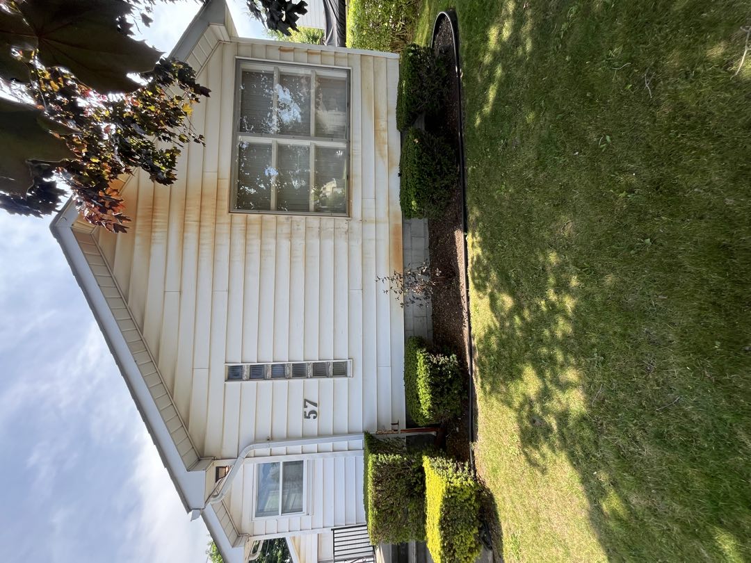 Vinyl siding covered in heavy rust and oxidation stains before cleaning
